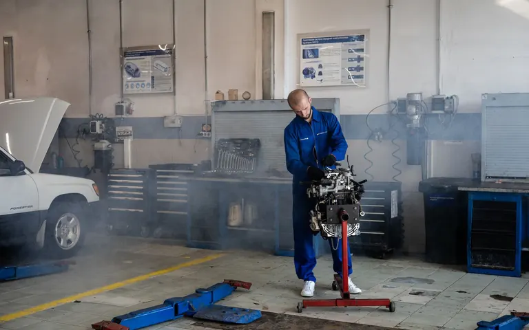 Mechanic working on a vehicle engine in an automotive workshop